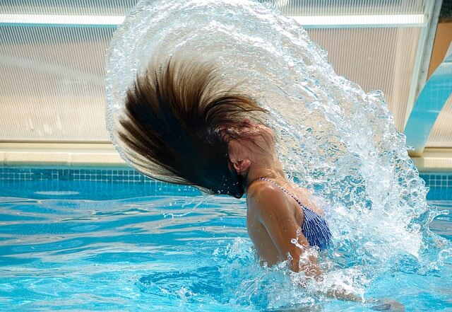 A young woman throwing her head back in a swimming pool. 