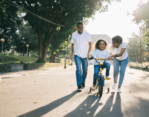 Man_Standing_Beside_His_Wife_Teaching_Their_Child_How_to_Ride_Bicycle