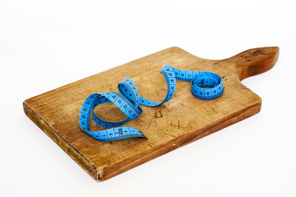 Measuring tape on an empty wooden cutting board.